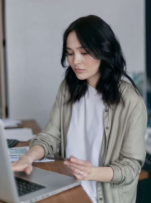 pexels photo 6964340 6964340 Focused young woman working on a laptop at her desk, managing finances.
